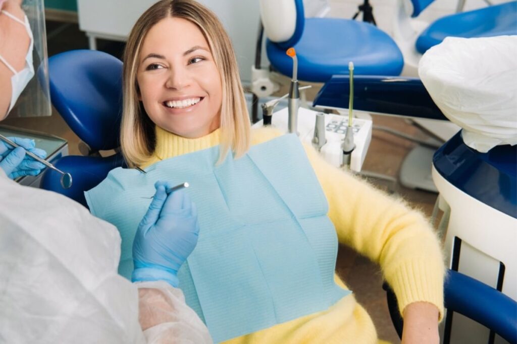 Smiling patient in dental chair holding bib during anxiety-free dental visit.