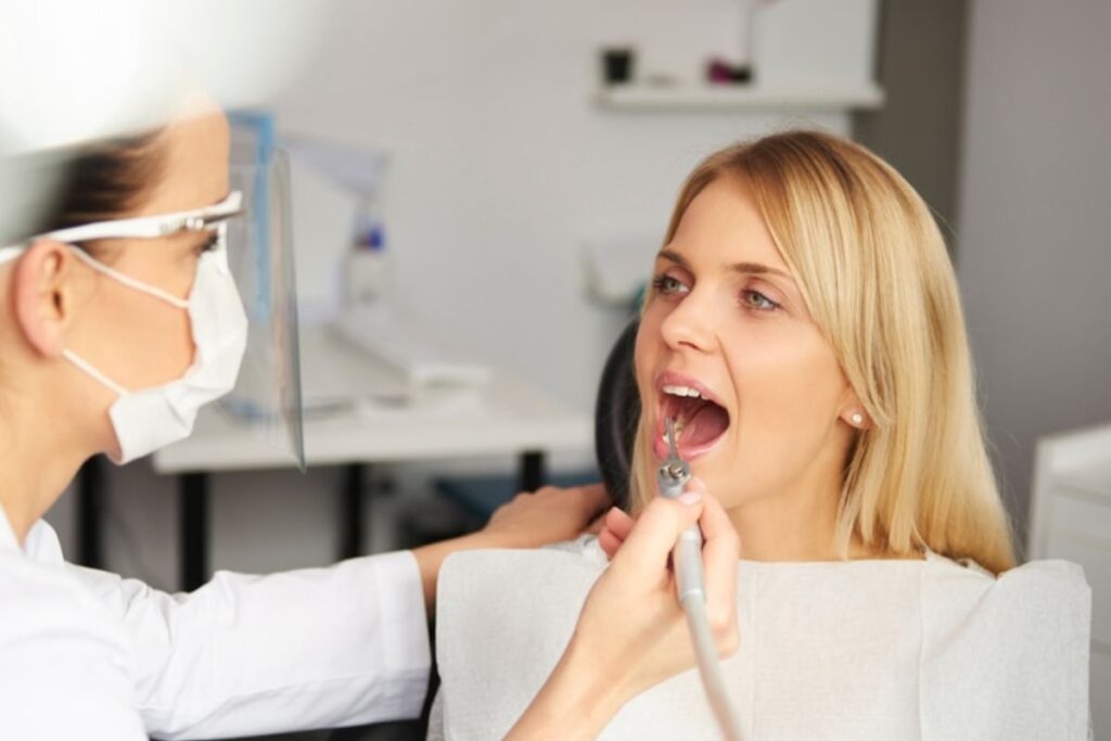 Dentist examining patient's teeth during oral examination at dental office.
