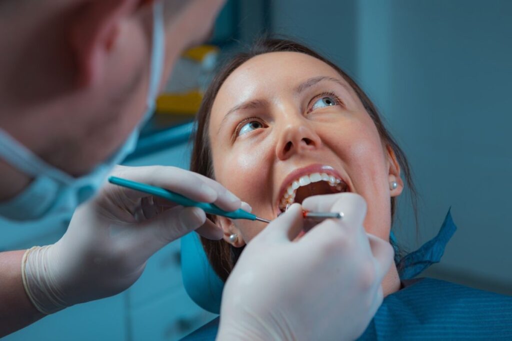 Dentist examining patient's teeth during regular checkup to prevent dental emergencies.