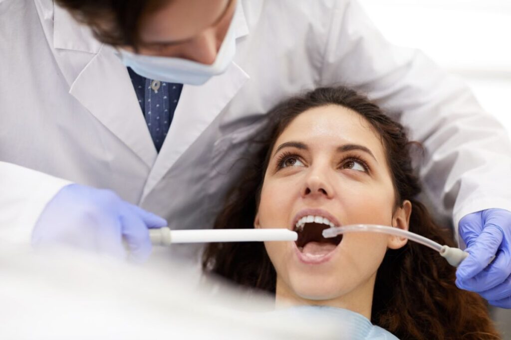 Dentist examining patient's teeth during professional cleaning at Huntley dental practice.