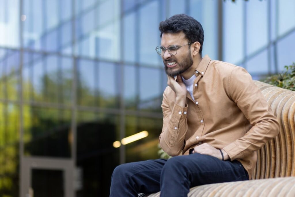 Man in glasses smiling while on phone call outdoors in modern setting.