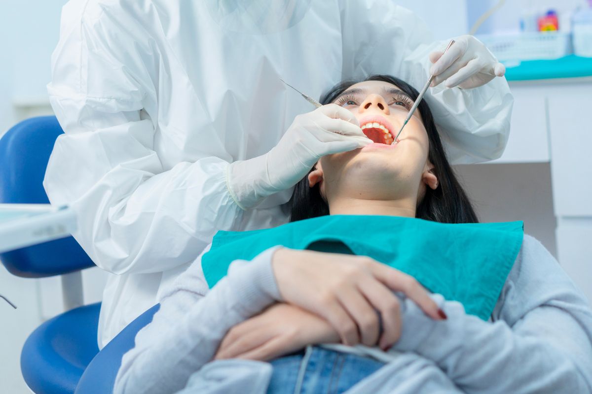 A dentist examining a patient’s teeth for cavities in a clinic.