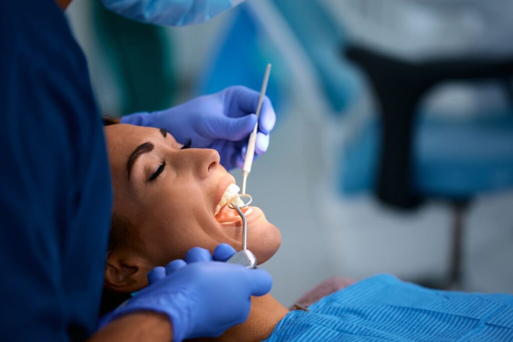 Dentist examining patient’s gums during checkup.