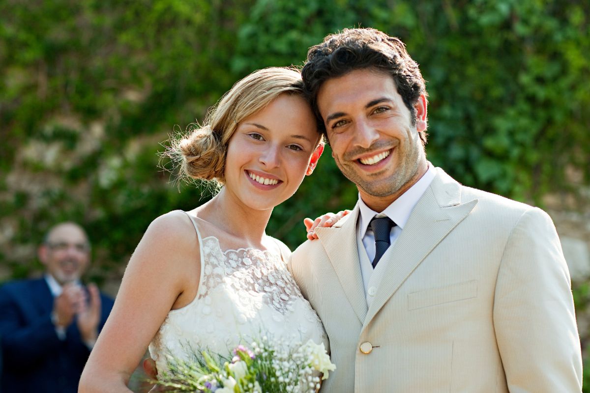 Groom and bride smiling with bright teeth after whitening treatment.