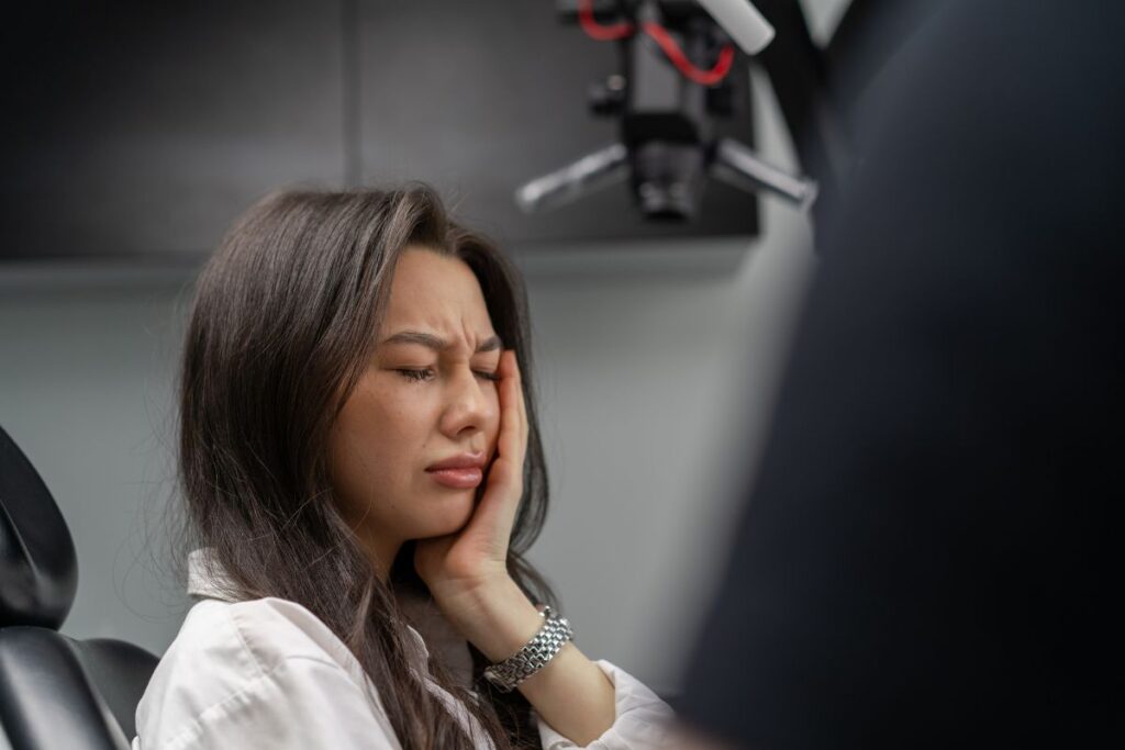 Woman experiencing toothache while visiting the dentist for emergency care.