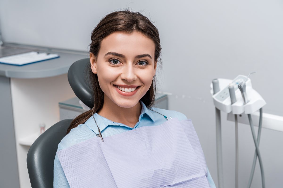 Woman smiling in a dental chair after professional teeth whitening treatment.