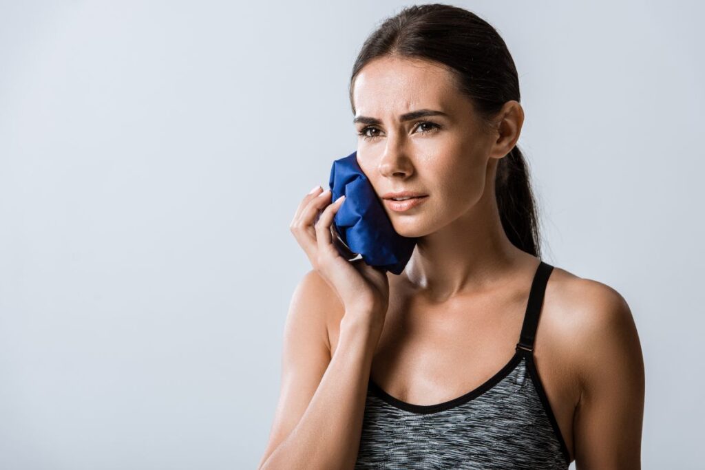 Person using a cold compress for toothache relief at home.