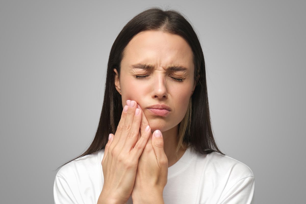 A woman touching her jaw due to stress-related tooth pain.
