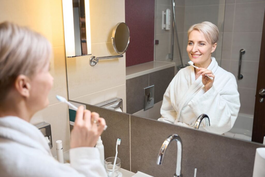 Person smiling with healthy teeth while brushing as part of a daily oral hygiene routine.