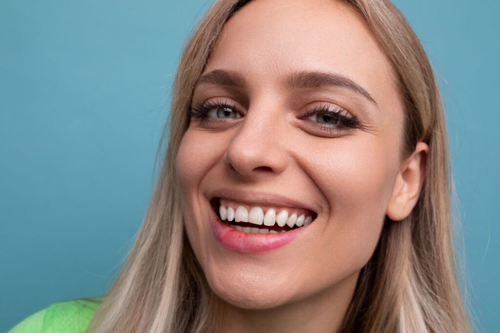 Woman smiling with bright white teeth after safe teeth whitening treatment designed for sensitive teeth.