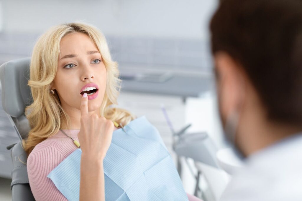 Patient in dental chair discussing teeth alignment concerns with dentist during Invisalign consultation.