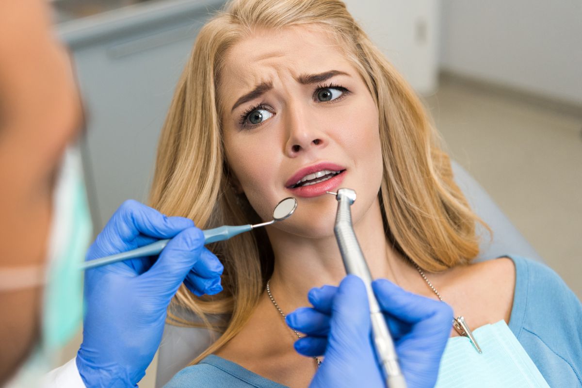 Patient with swollen gums looking anxious during emergency dental examination in clinic chair.