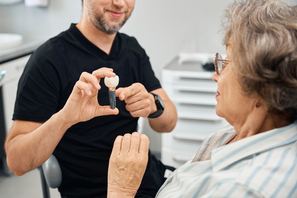 Dentist showing dental implant model to patient.