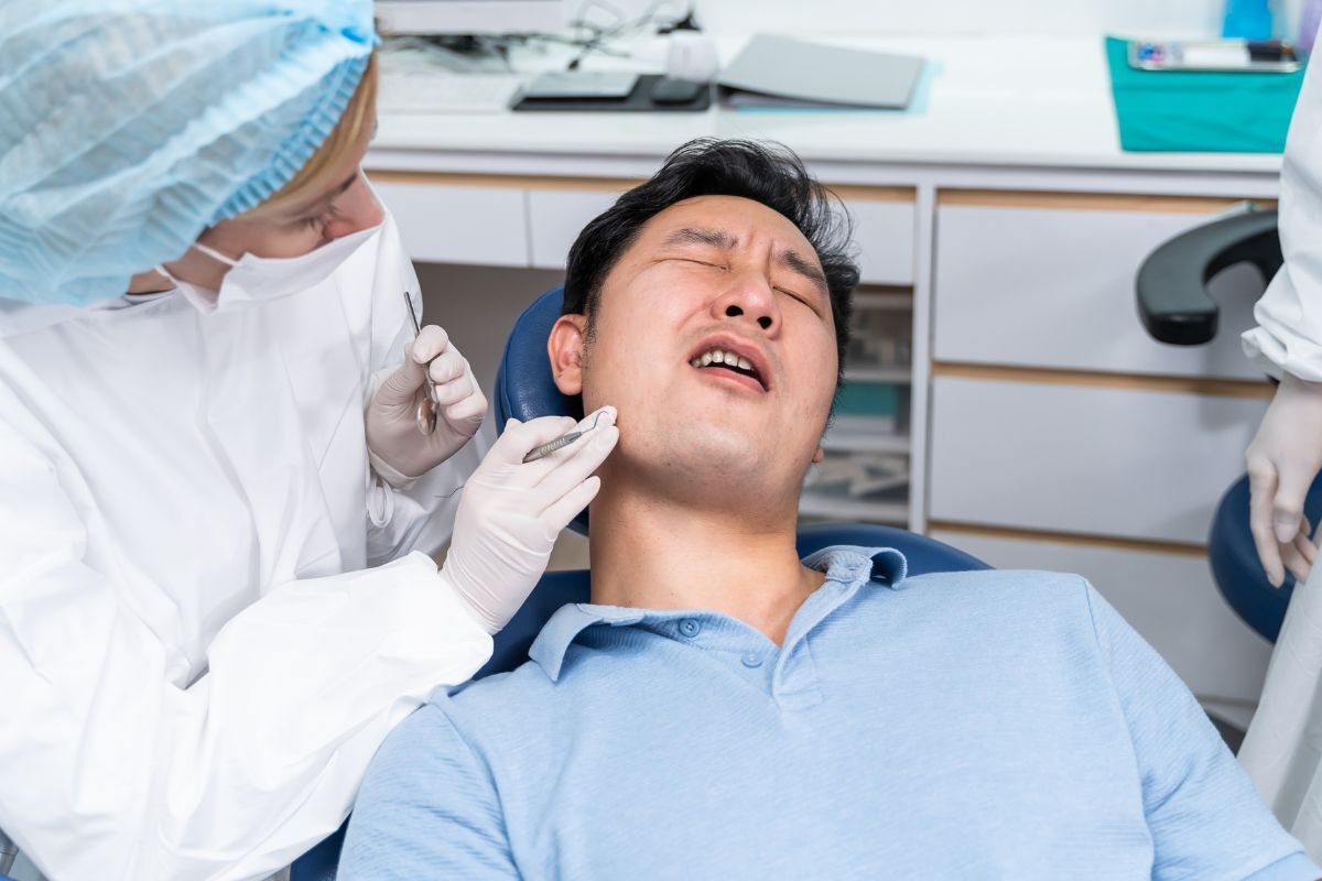 Emergency dentist examining patient's teeth in dental office.