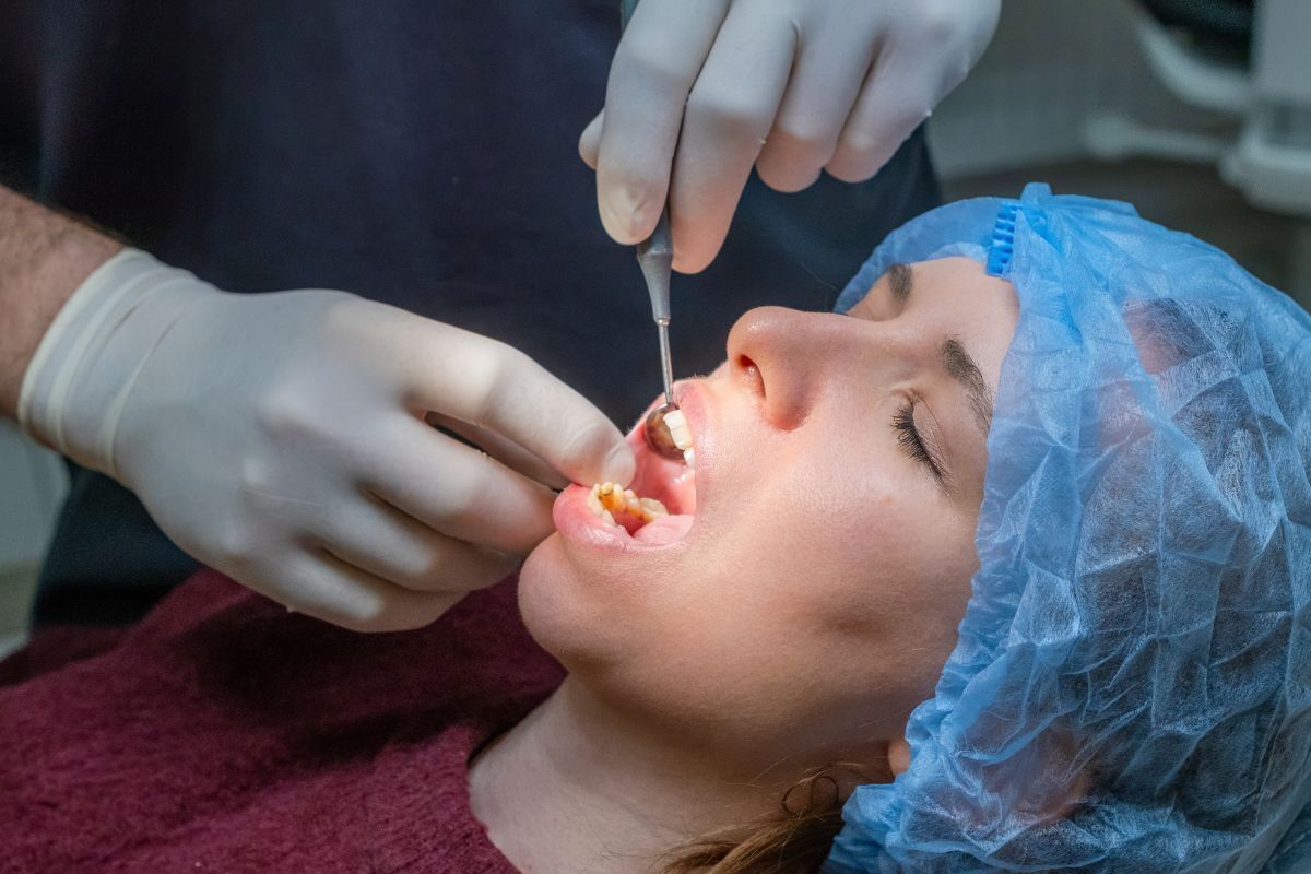 Dentist examining patient's teeth and gums during dental treatment procedure.