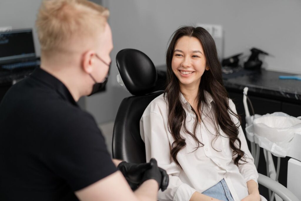 Male dentist in black gloves consulting with female patient in dental chair at Huntley practice.