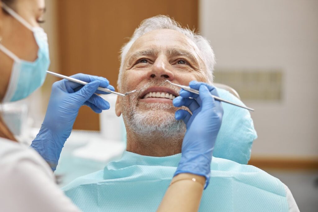 Dentist examining senior male patient's teeth during routine dental checkup in Huntley.