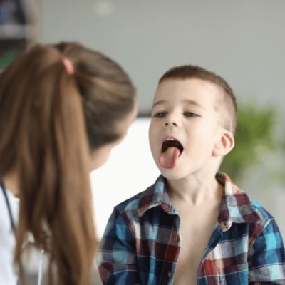 Young boy sticking out his tongue during a dental exam with a dentist.