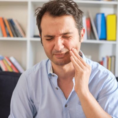 Man holding his cheek in pain at dental office in Huntley, IL.